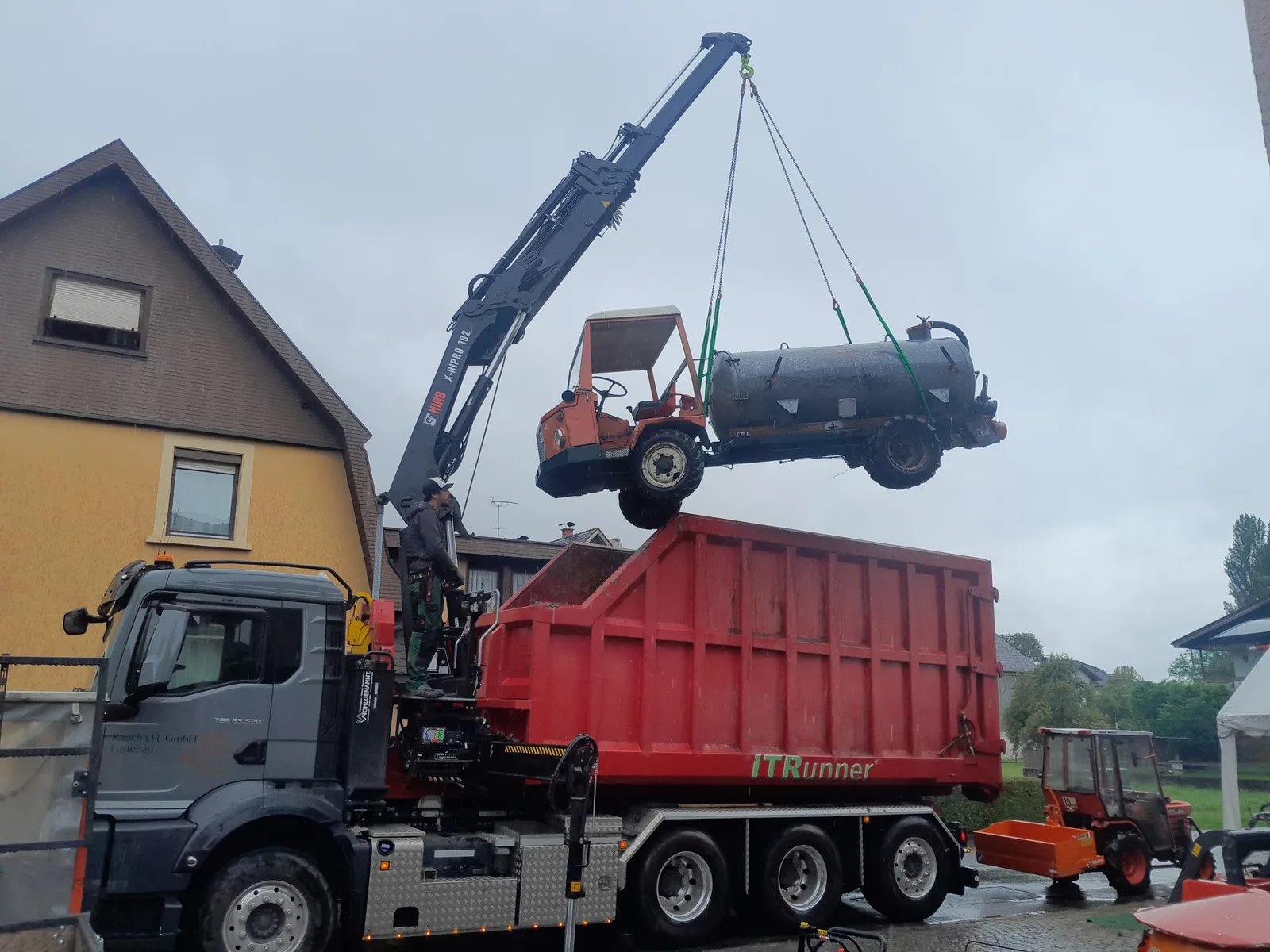 Kranwagen hebt einen alten Transporter über einen Container